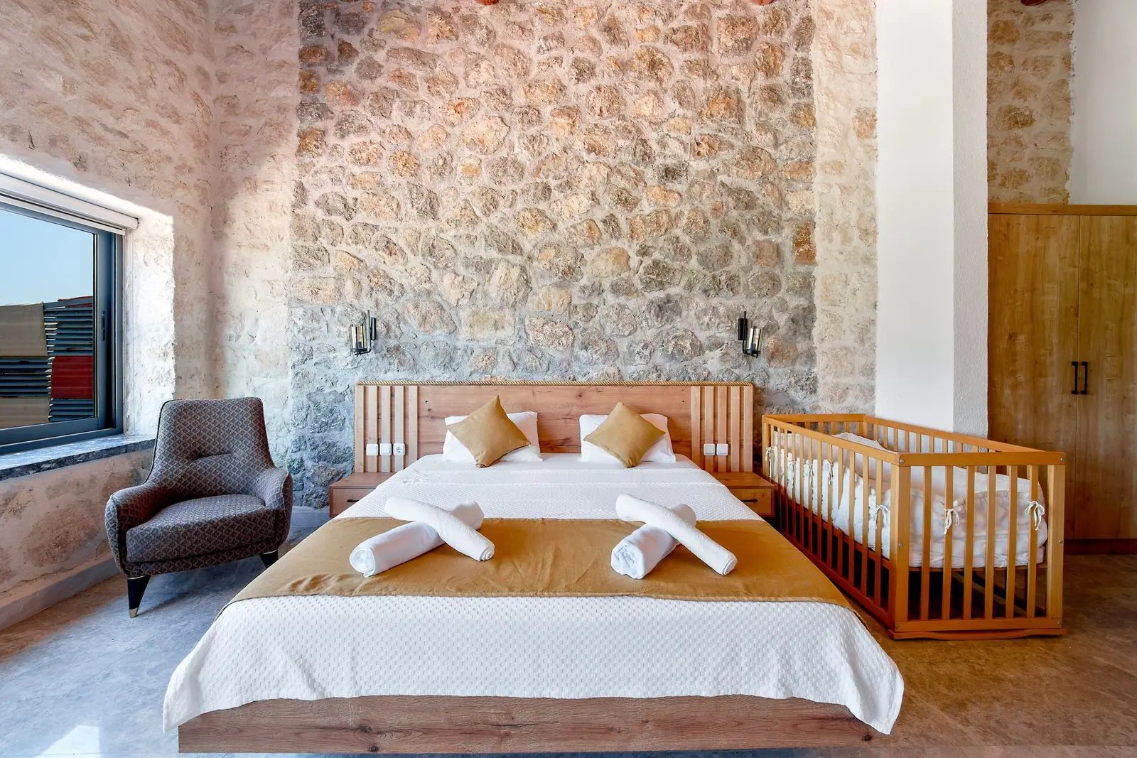 A wooden crib placed beside a double bed in a bedroom