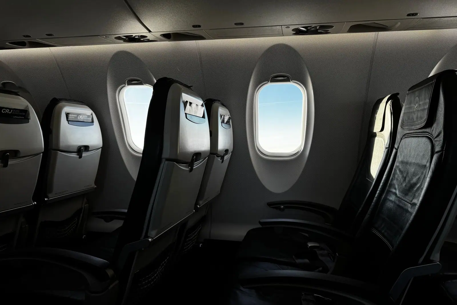 A row of empty aircraft seats beside cabin windows