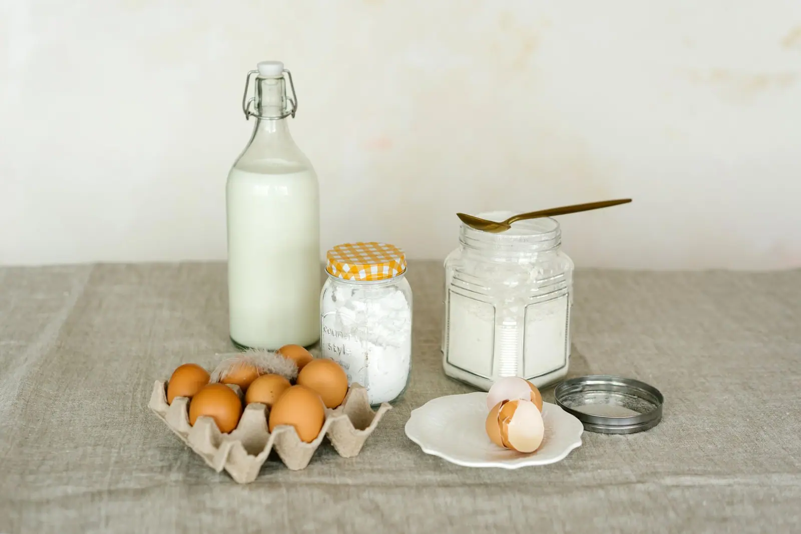 A bottle of milk, a carton of eggs and storage jars on a table